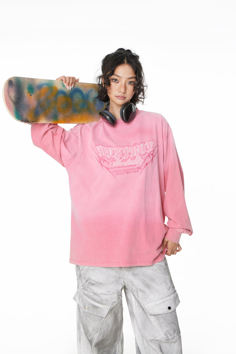 Model wearing pink gradient washed long sleeve tee with front graphic and skateboard