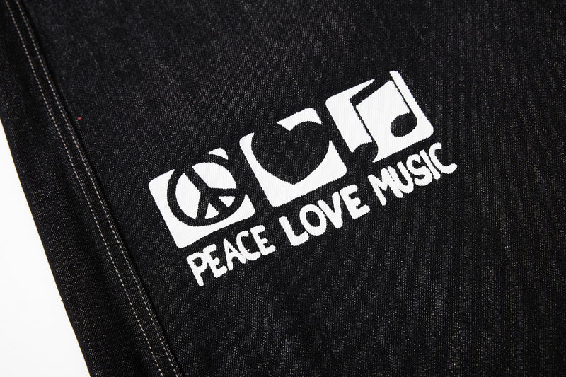 Close-up of peace love music graphic on black denim jeans