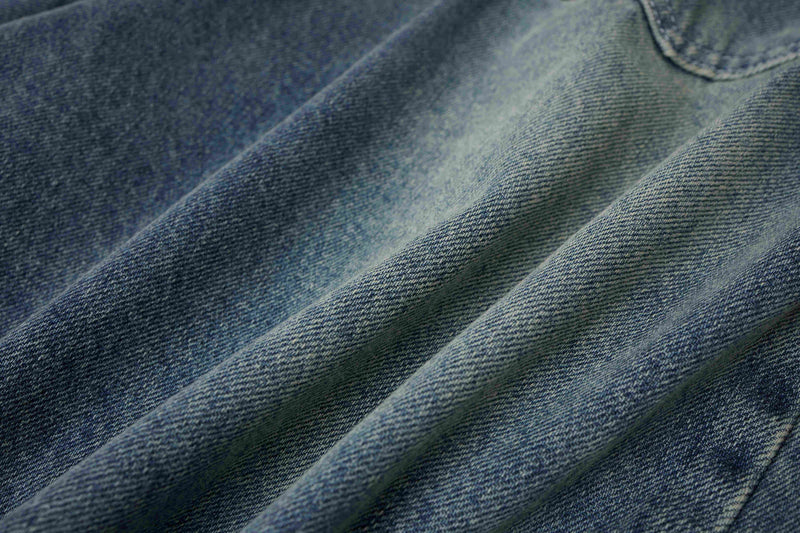 Close-up of light wash denim fabric texture with soft diagonal folds