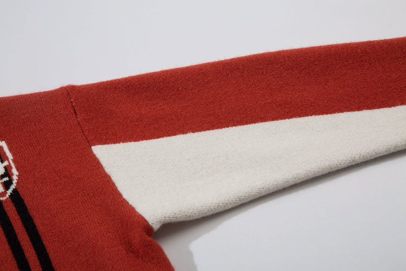 Close-up of red and white sleeve color block on cable-knit jacket