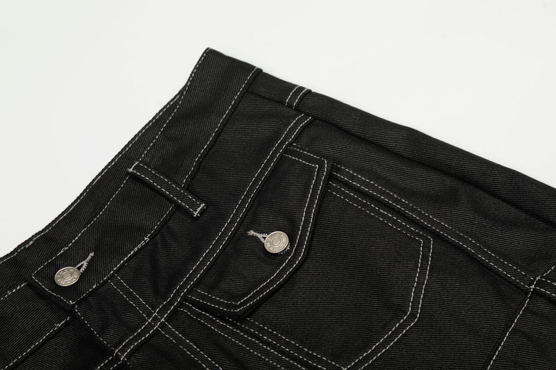 Close-up of the back waist on black denim pants with contrast stitching and pocket flap