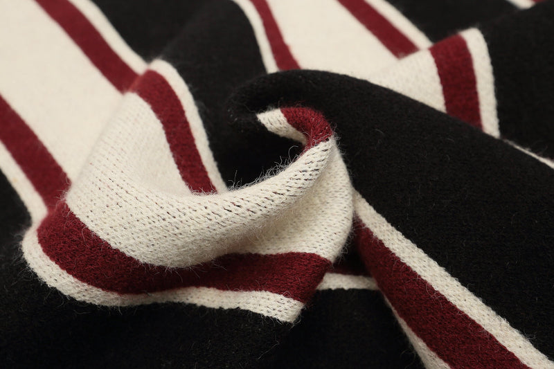 Close-up of soft knit fabric fold showing cream and burgundy stripes on black sweater