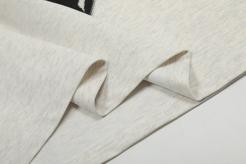 Close-up of an oversized cream graphic tee sleeve with stitched hem and soft textured cotton fabric
