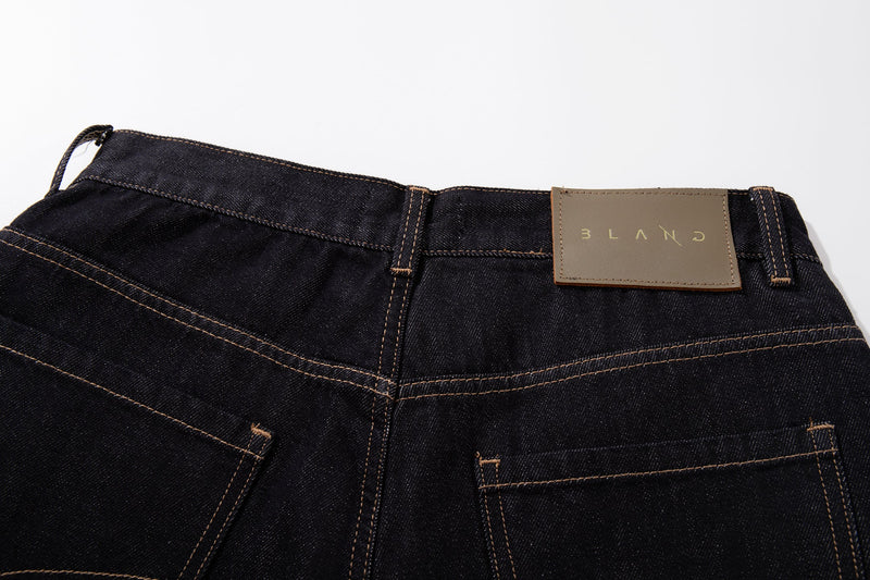 Back waistband close-up of dark wash jeans with tan label and belt loops