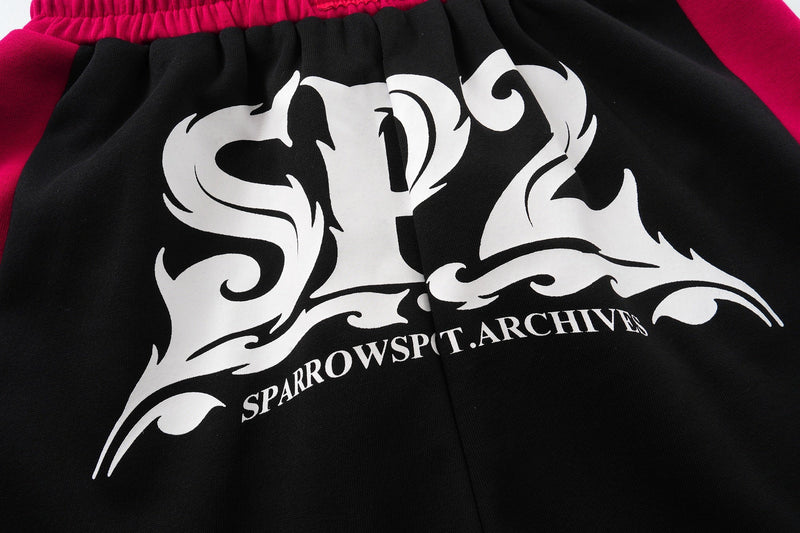 Close-up front logo graphic on black shorts with magenta side panels