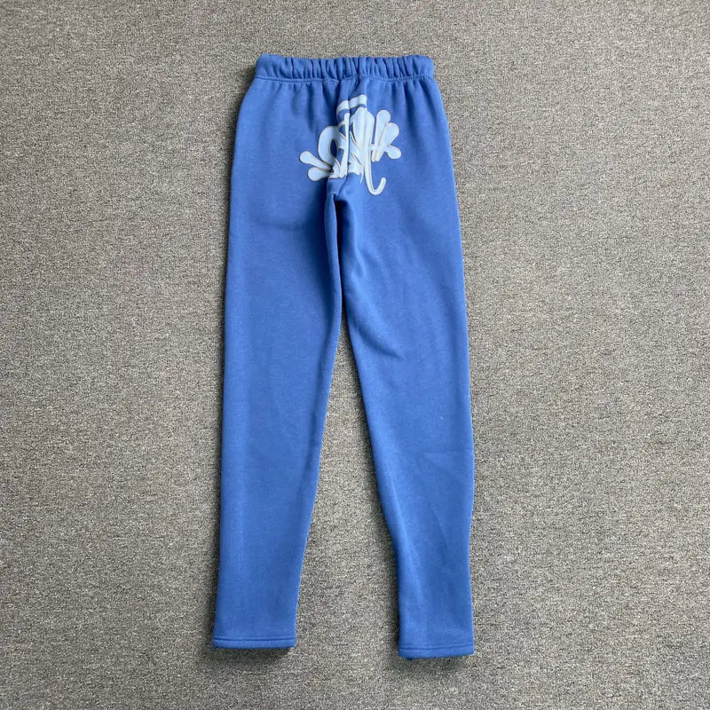 Syna World Blue Letter Print Drawstring Jogger Pants with elastic waistband shown on a gray carpet feature a bold white splatter design on the upper back, giving these joggers a trendy streetwear style.