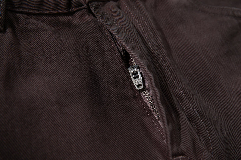 Close-up of the front fly zipper on brown denim jeans