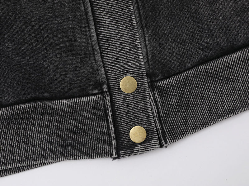 Close-up of black jacket hem with ribbed waistband and snap buttons