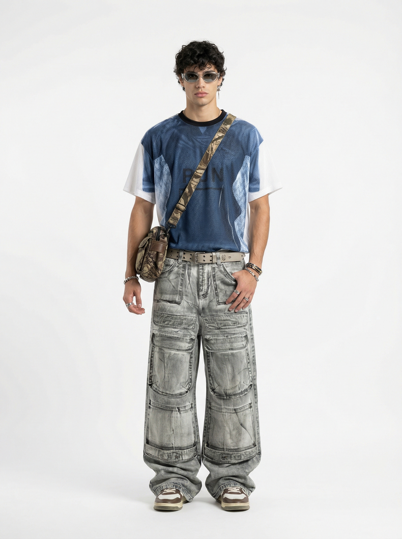 Model wearing a blue graphic mesh jersey with white sleeves, gray cargo jeans, sunglasses, and a camo crossbody bag on a white background