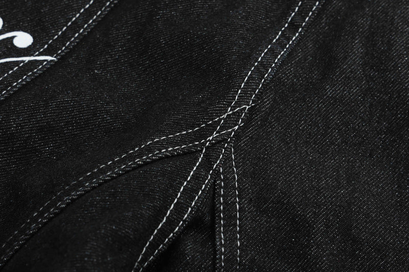 Close-up of black denim seam lines and folded fabric texture