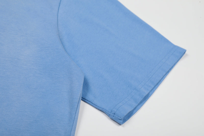 Light blue cotton graphic tee sleeve with neat hem stitching on a clean white background