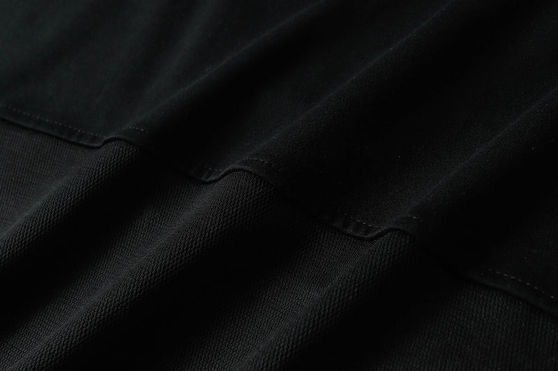 Close-up of black oversized V-neck street tee fabric with subtle split stripe texture and stitched detail