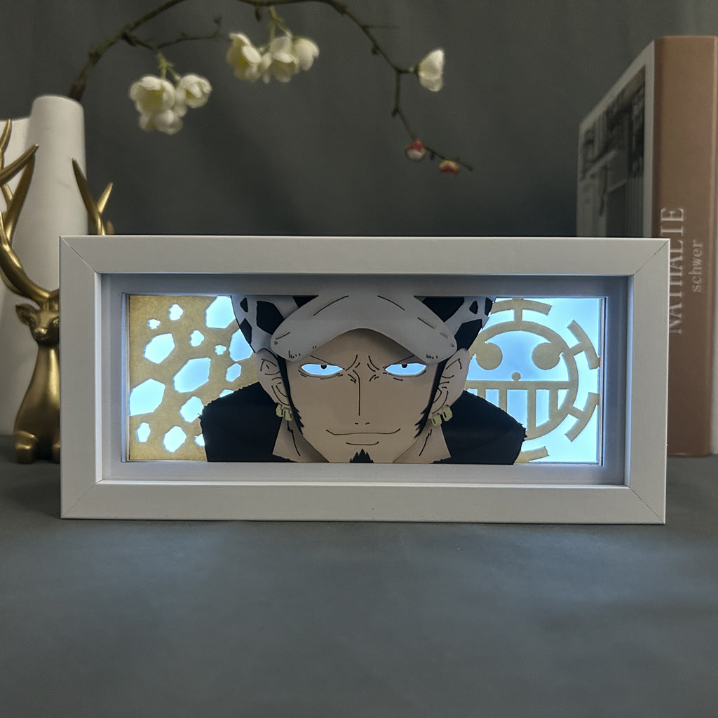 The Seakoff One Piece Anime Light Box features Trafalgar D. Water Law as a 3D LED lamp with dynamic color-changing effects, highlighting his intense gaze, signature spotted hat, and black coat against a honeycomb-patterned backdrop. It rests elegantly on any surface surrounded by decorative items.