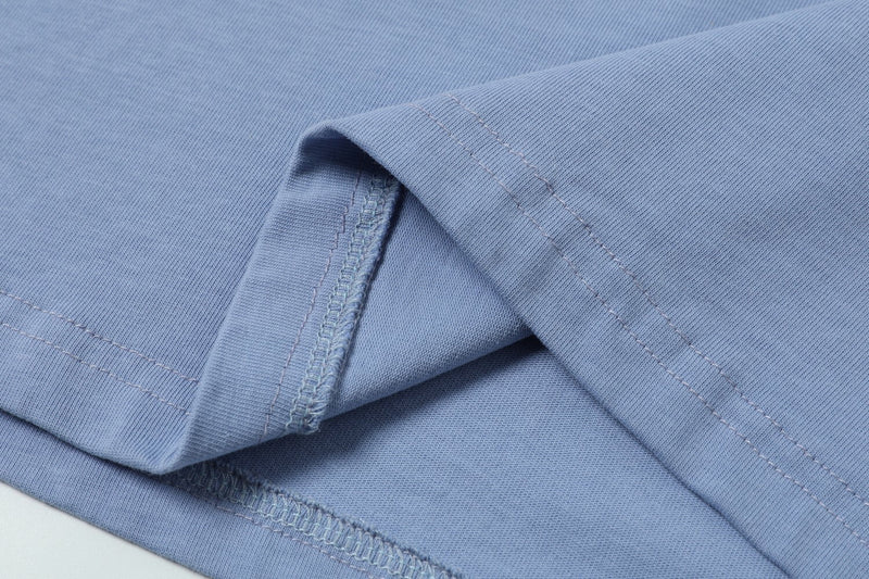 Close-up of the sleeve seam and cuff stitching on a light blue T-shirt