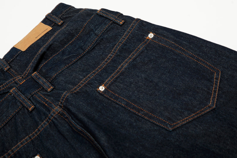 Close-up of back pocket and waistband detail on deep indigo jeans with contrast topstitching