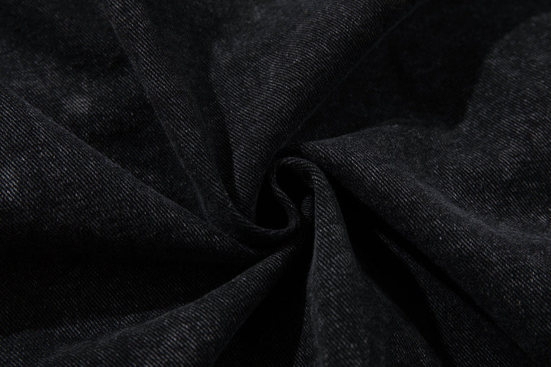 Close-up of gathered black denim fabric showing soft folds and texture