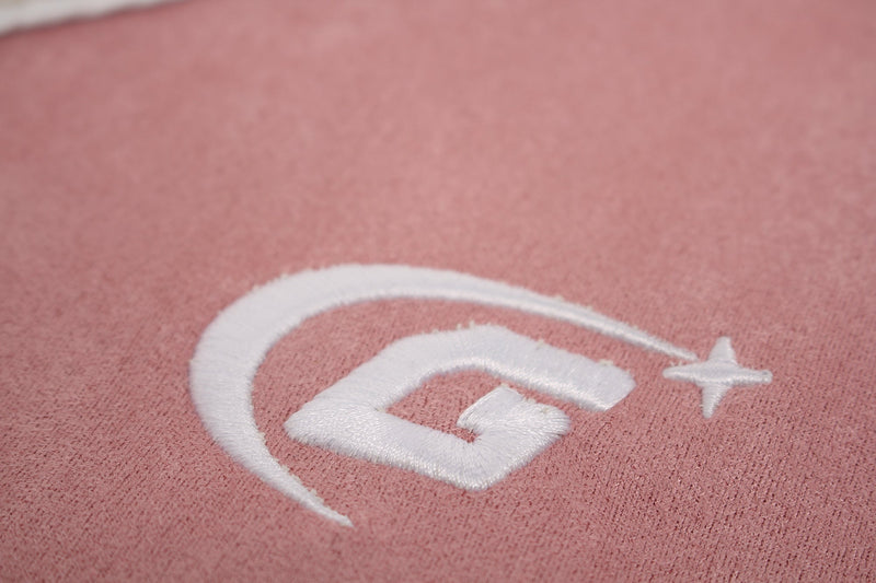 Close-up of pink suede-textured T-shirt fabric with white embroidered logo detail