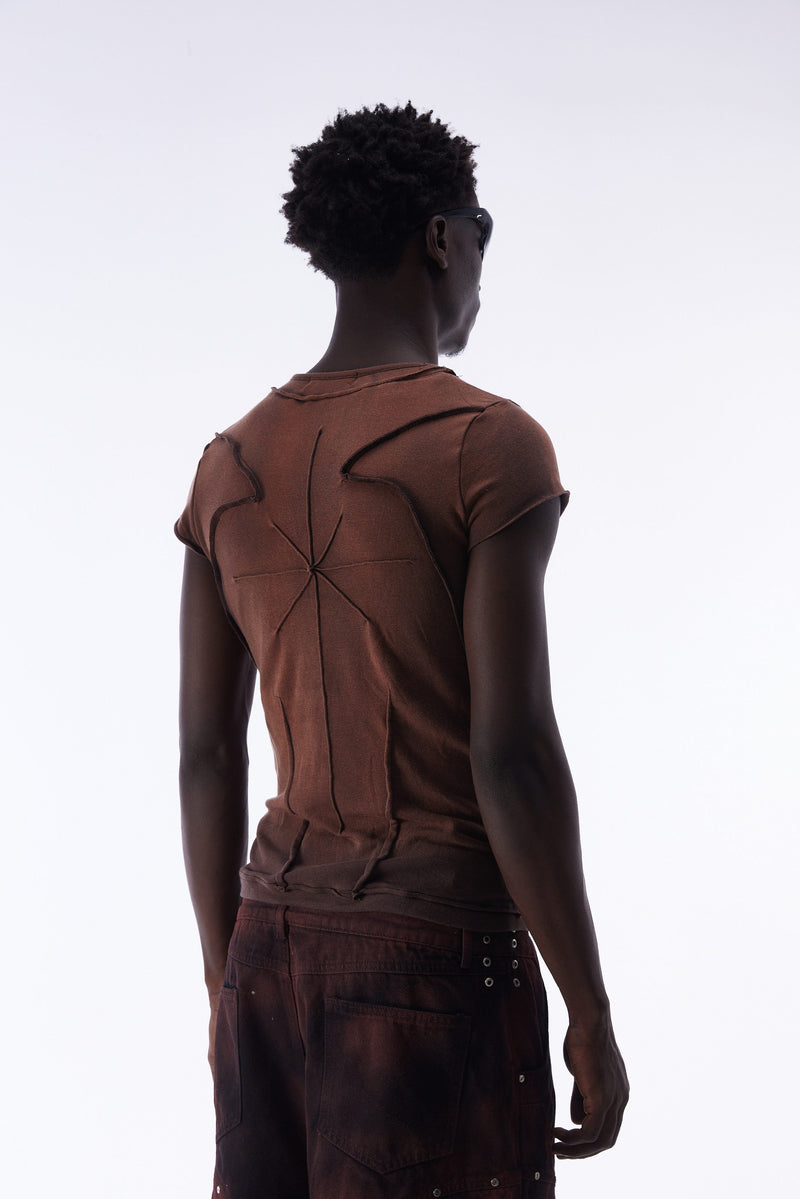 Model wearing a brown sculpted cotton tee with raw seam paneling and an avant-garde fitted silhouette from the back