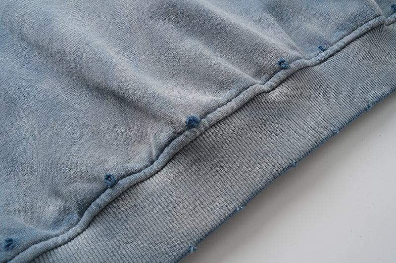 Close-up of faded blue hoodie hem with ribbed waistband and seam details