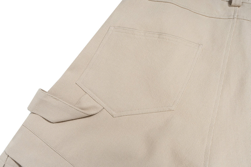 Close-up of beige cargo shorts side pocket and layered panel stitching