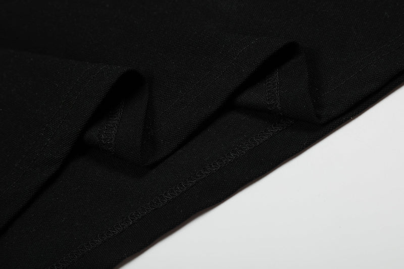 Close-up of black polo shirt fabric with visible stitching and hem detail on a clean white background