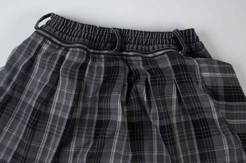 Close-up of black plaid overlay at the waistband on wide-leg baggy jeans