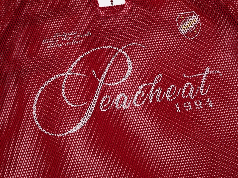 Red mesh vintage polo tee with white script graphic and crest detail on the chest
