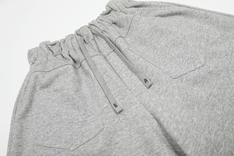 Gray drawstring waistband and front pocket detail on wide lounge shorts