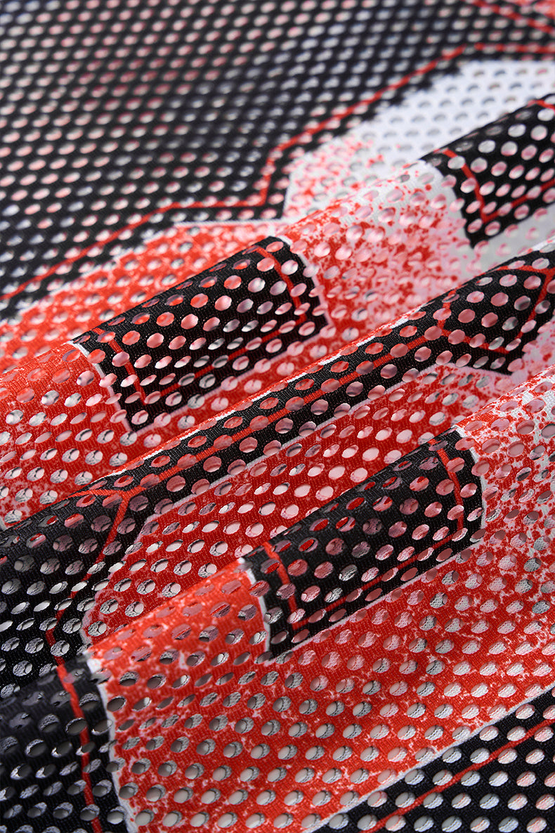 Close-up of black, red and white mesh jersey fabric with bold flame-style pattern and perforated streetwear texture