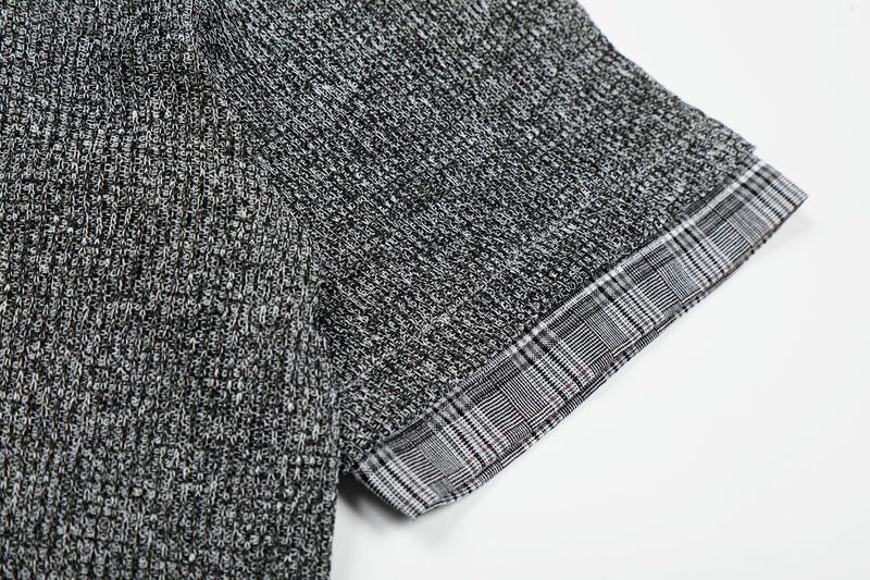 Close-up of a black and white layered knit check shirt sleeve with textured cotton fabric and plaid cuff trim
