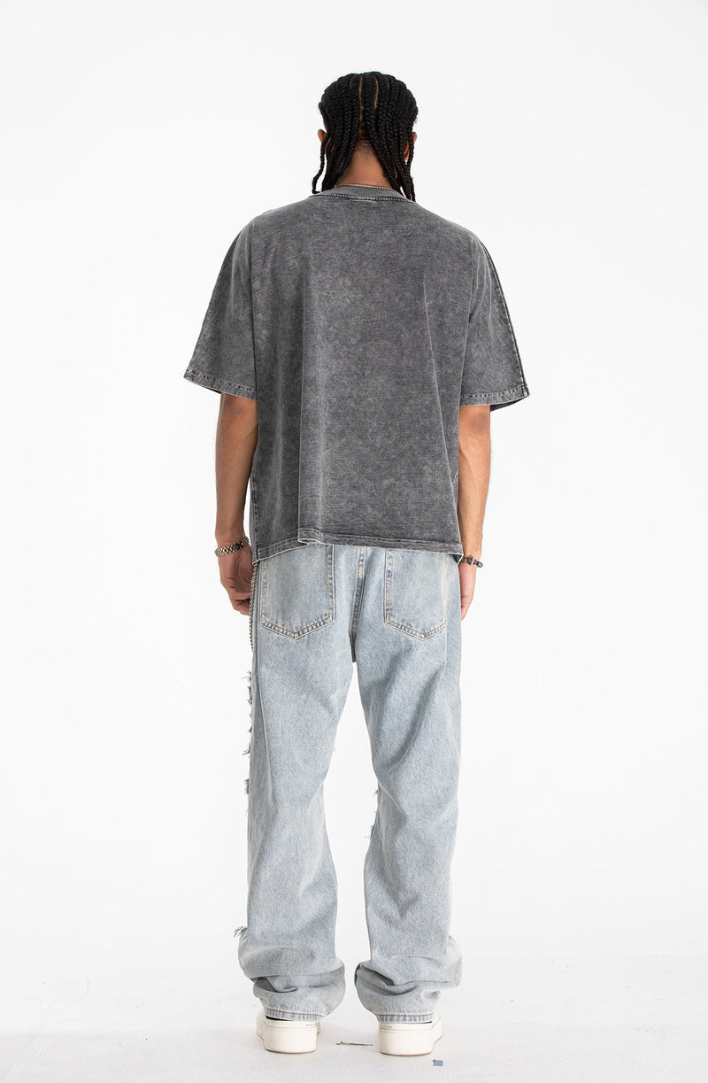 Back view of a vintage wash oversized gray graphic tee styled with light wash jeans and white sneakers