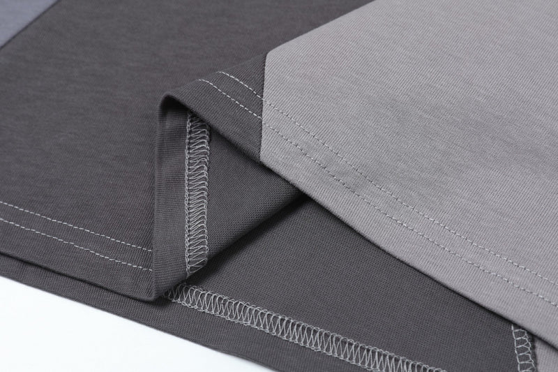 Close-up of layered gray panel split T-shirts with visible stitching and ribbed cotton fabric texture