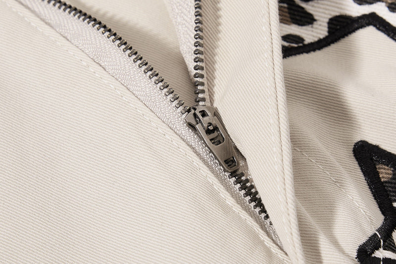 Close-up of beige pants zipper fly with leopard star fabric beside it