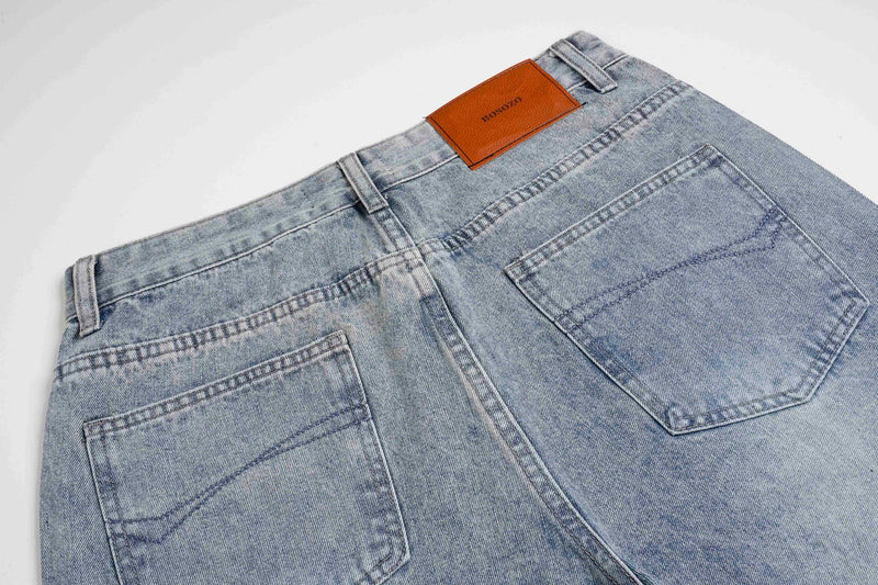 Close-up of light wash jeans back waist with leather logo patch