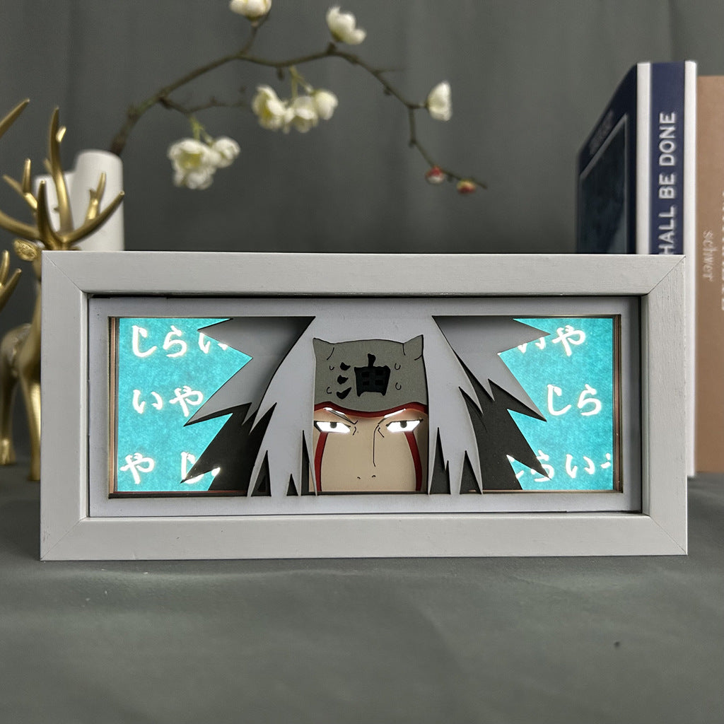 The Naruto Anime Light Box – Jiraiya showcases an anime character with long white hair and red markings. It features a teal background with Japanese characters and includes a blurred faux deer and branches with white flowers, creating depth in this 16-color adjustable LED scene.