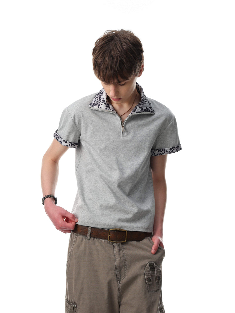 Light gray quarter-zip polo shirt with leopard print collar and sleeve trim, styled with casual streetwear pants
