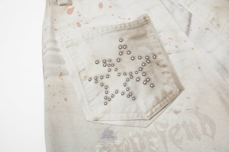 Close-up of back pocket with star-shaped stud pattern on cream jeans