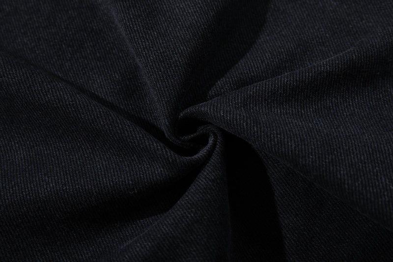 Close-up of black denim fabric texture with diagonal weave and soft folds