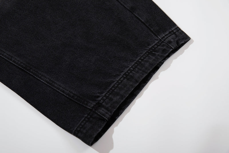 Cropped hem detail of washed black denim wide-leg jeans with straight stitched cuff