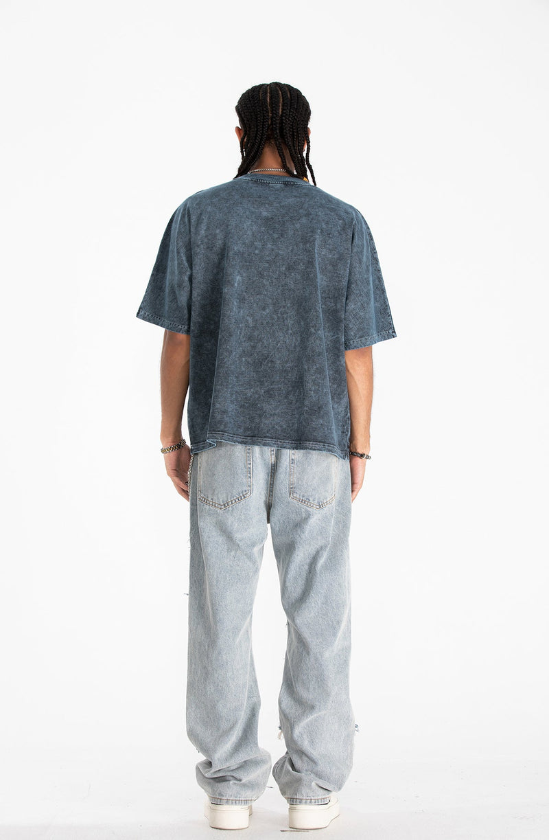 Back view of a washed black oversized gothic tee styled with light baggy jeans and white sneakers