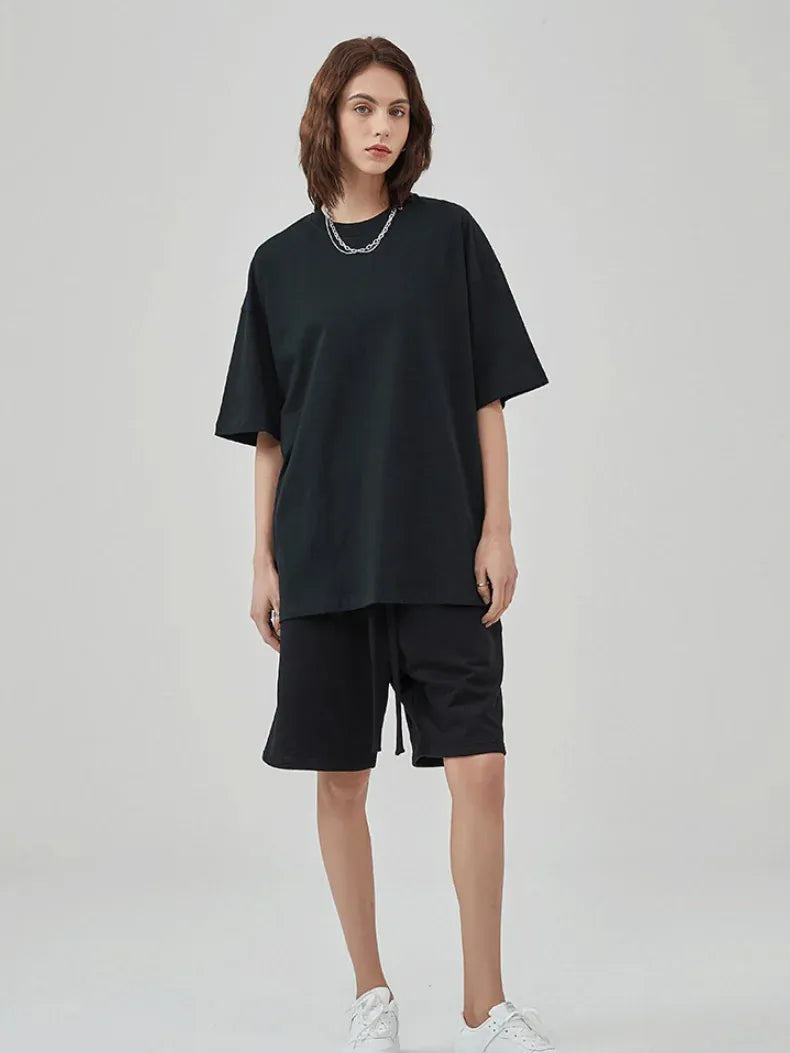 A person stands against a plain background wearing a Custom Anime Character Black T-Shirt - Personalized 230GSM 100% Cotton Tee, black knee-length shorts, white sneakers, and a silver necklace.