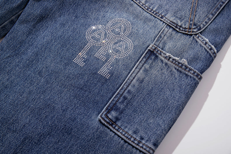 Close-up of blue denim side utility pocket and rhinestone key graphic
