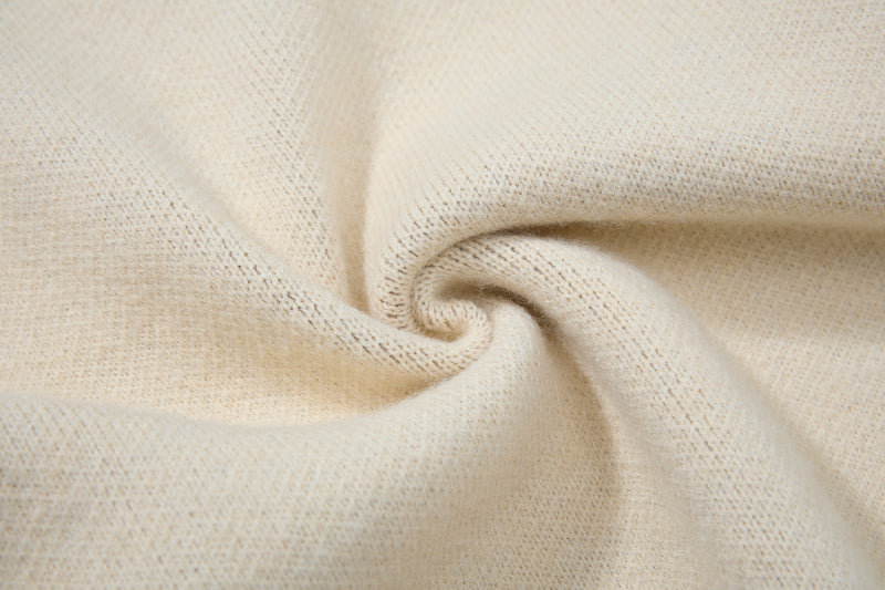 Close-up of cream knit fabric texture with soft folded swirl