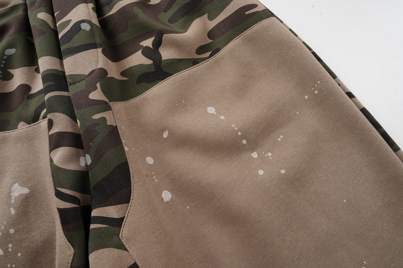 Close-up of tan patch pocket and camo fabric with white paint splatter