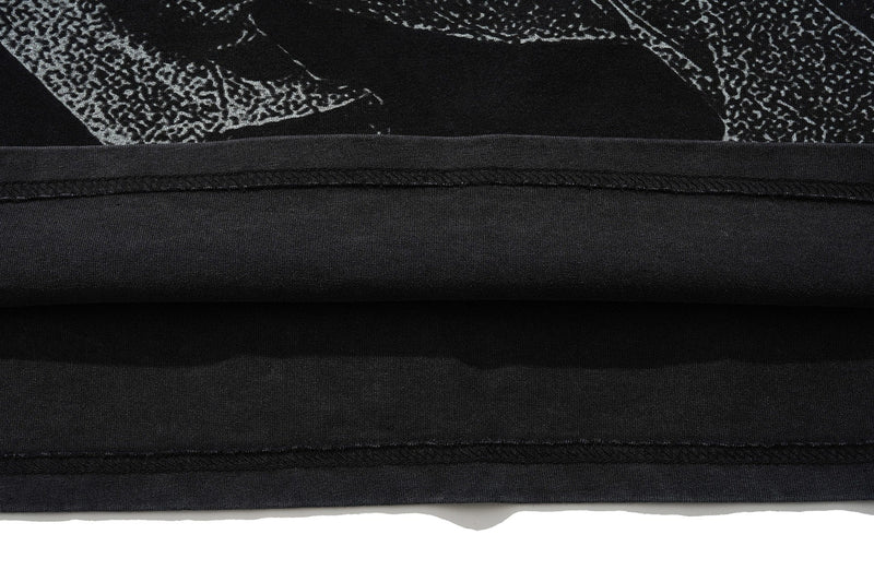 Close-up of a black oversized graphic tee with vintage wash and visible hem stitching detail