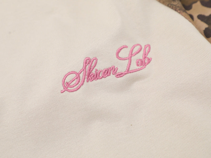 Close-up of pink embroidered script logo on cream fabric