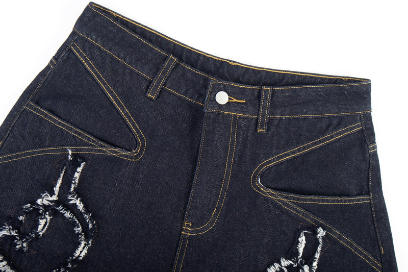 Close-up of the front waistband on dark jeans with button closure and contrast stitching