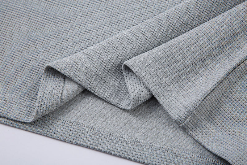 Close-up of gray textured half-zip streetwear T-shirt fabric with folded sleeves and visible stitching