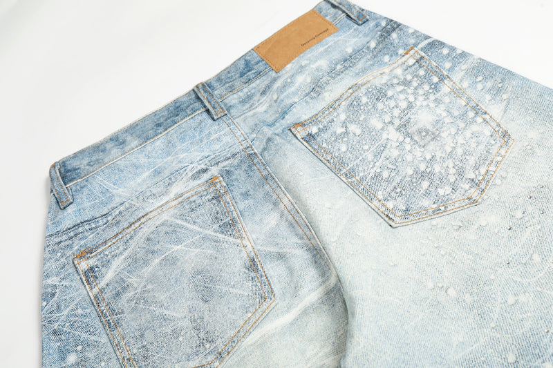 Back waistband and pockets of light wash jeans with tan logo patch and spiderweb finish