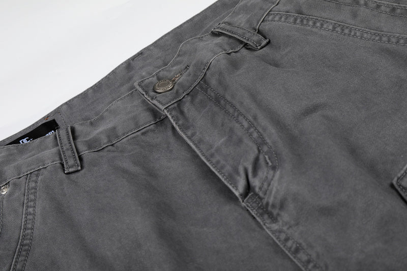 Close-up of gray shorts front pocket detail with stitched seams and button closure
